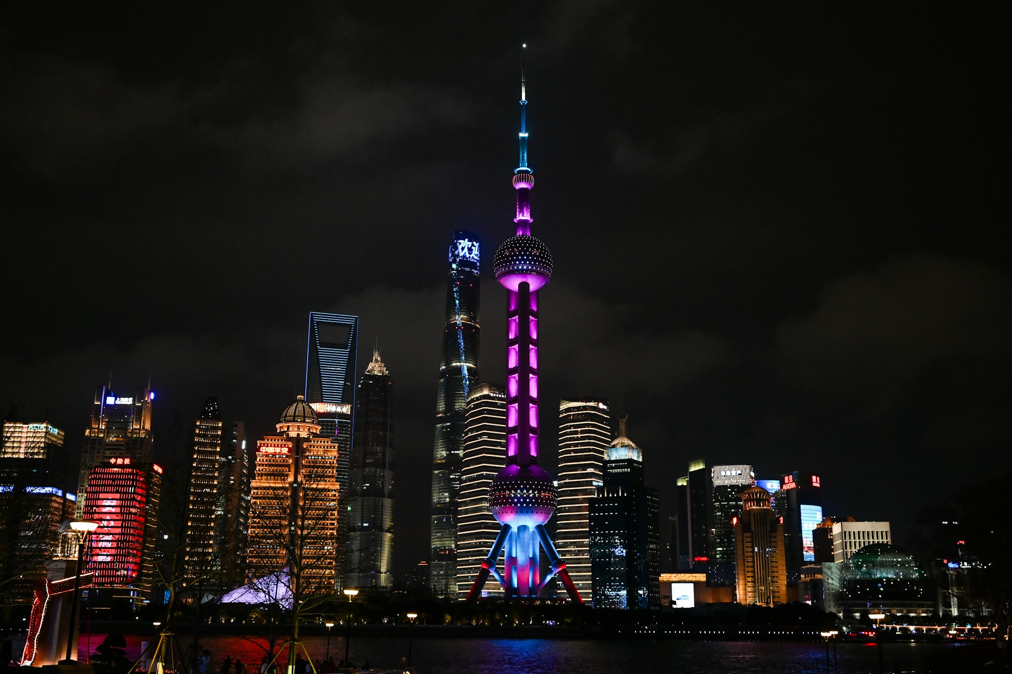 The Oriental Pearl Tower glowing purple beside Shanghai’s illuminated skyline at night